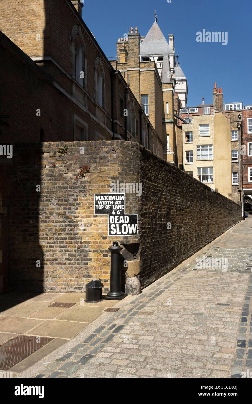 Camminando lungo Temple, Londra. Il cartello "Dead Slow" avvisa i conducenti della corsia stretta davanti a loro. Foto Stock