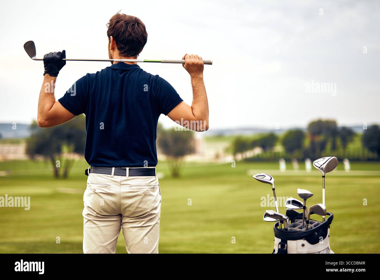 Un golfista esperto si trova in un campo incontaminato, pronto a giocare. Il paesaggio mozzafiato esalta la sua emozione, creando un ambiente perfetto Foto Stock