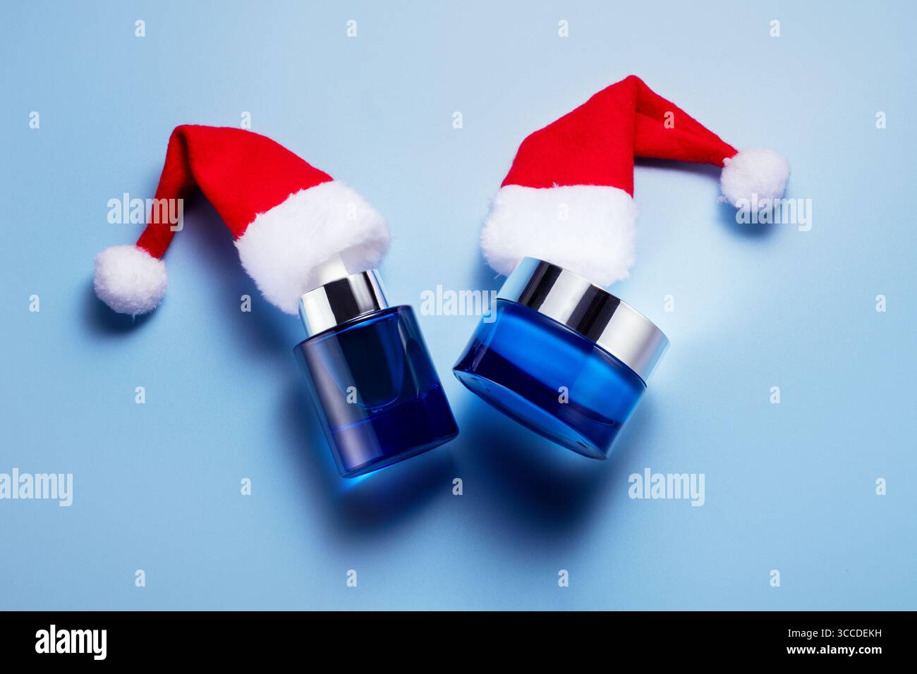 Concetto di cura della pelle natalizia con crema idratante blu e bottiglia di siero con cappelli. Allegra atmosfera di vacanza, concetto di prodotti di bellezza invernali, Foto Stock