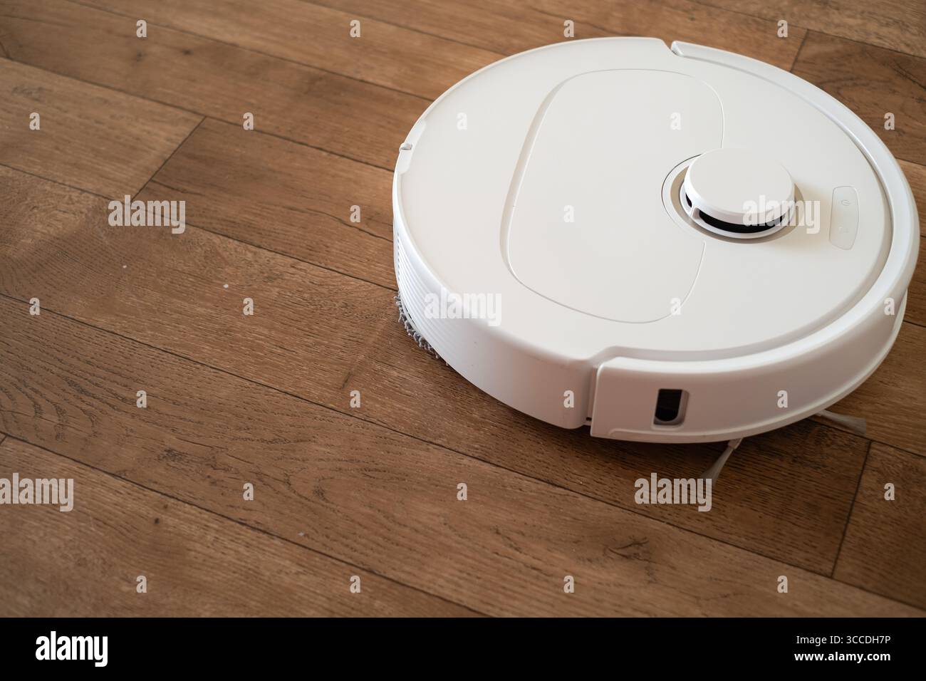 L'aspirapolvere robot pulisce il processo di pulizia automatica dei pavimenti senza l'intervento umano, la tecnologia Smart Home è in azione. Foto Stock