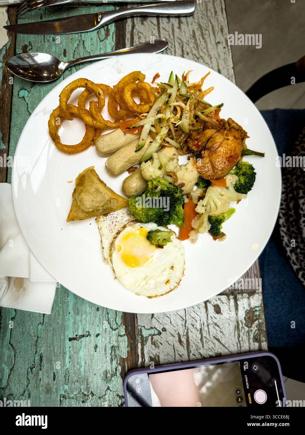 Vista dall'alto piatto piatto misto con uova fritte, anelli di cipolla broccoli samosa con verdure su un tavolo rustico nel Cafe Restaurant kuala lumpur malesia Foto Stock