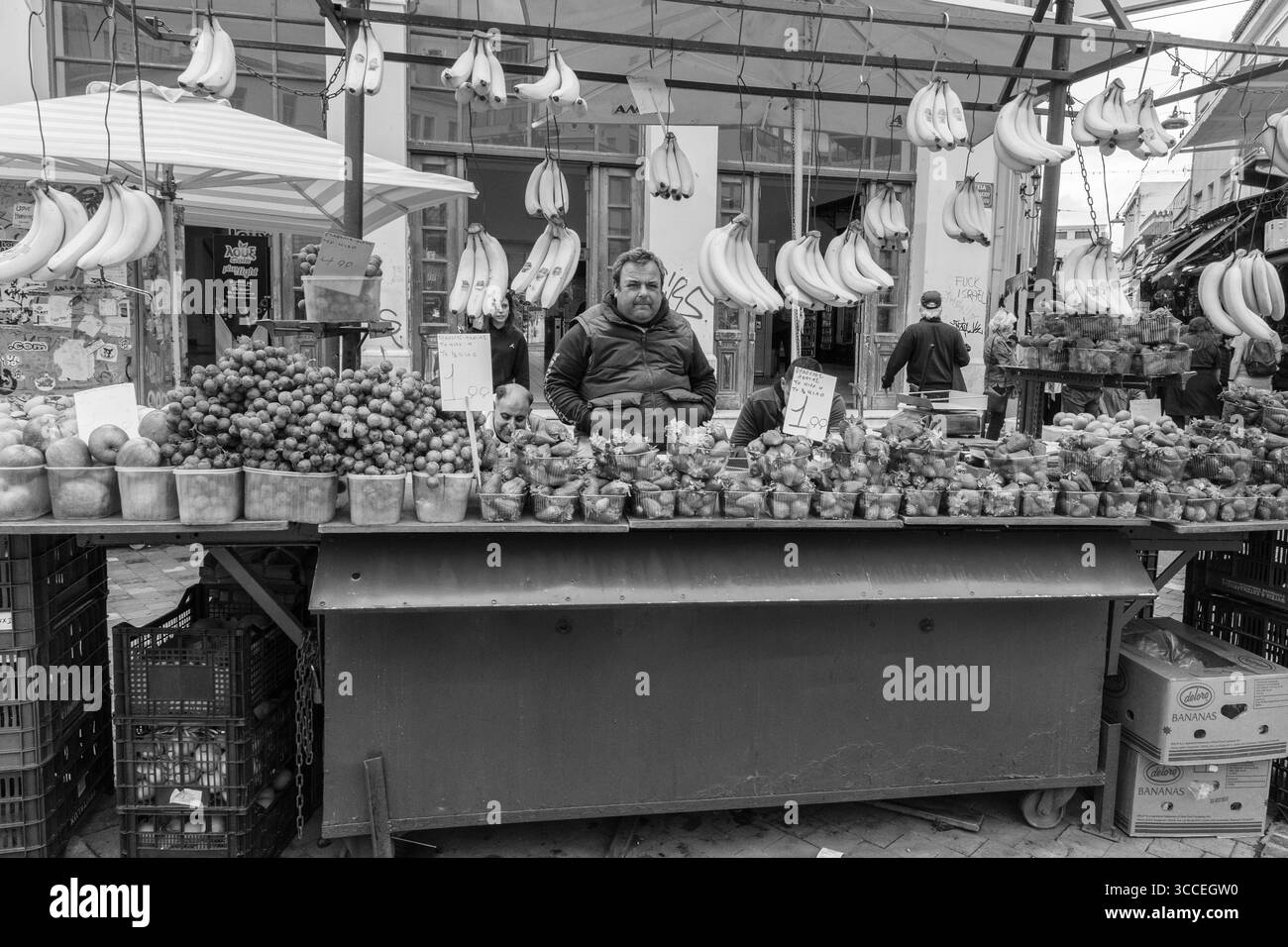 Vista a livello della strada, primo piano di un uomo che prepara frutta in una vivace bancarella di strada ad Atene, Grecia. Foto Stock