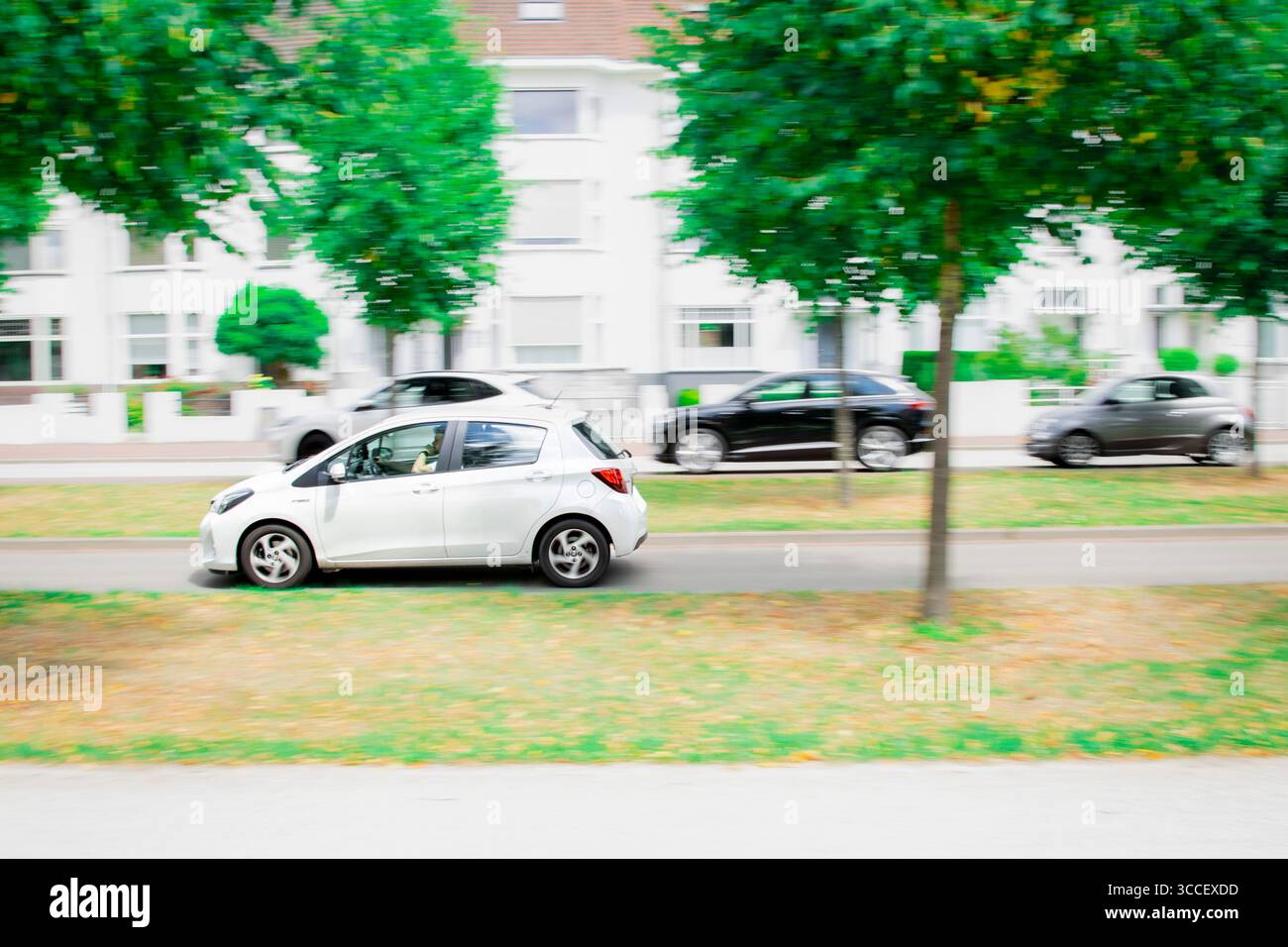 Un'immagine vibrante che cattura una berlina bianca in movimento dinamico, simboleggia la natura frenetica della vita cittadina e gli spostamenti quotidiani. Foto Stock
