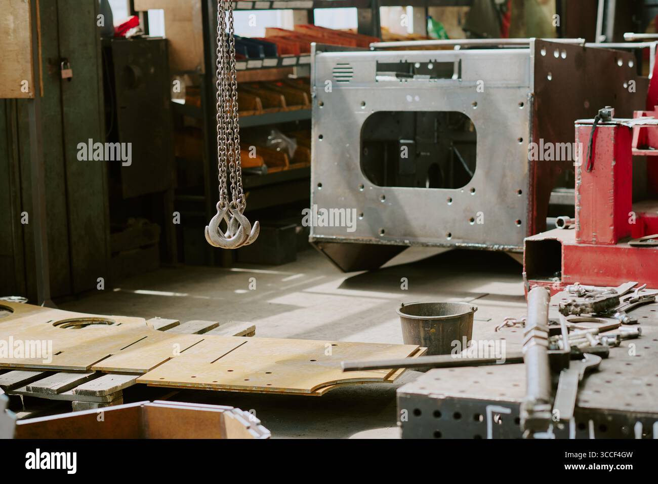 Officina industriale che mostra catene metalliche appese sopra macchinari e utensili Foto Stock