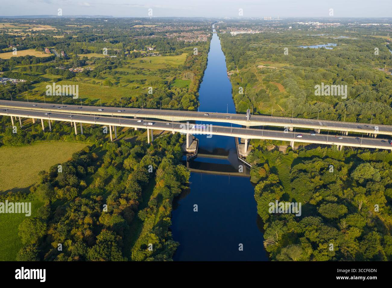 Immagine aerea dell'autostrada M6 sul viadotto di Thelwall che attraversa il fiume Mersey vicino a Warrington, con lussureggianti boschi verdi e campagna aperta Foto Stock
