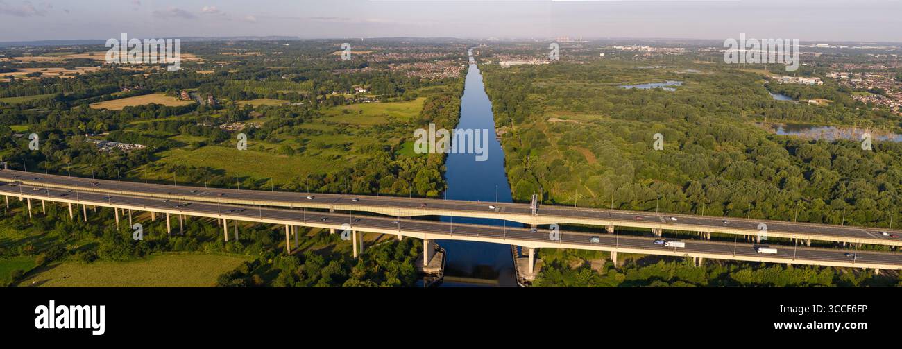 Immagine aerea dell'autostrada M6 sul viadotto di Thelwall che attraversa il fiume Mersey vicino a Warrington, con lussureggianti boschi verdi e campagna aperta Foto Stock