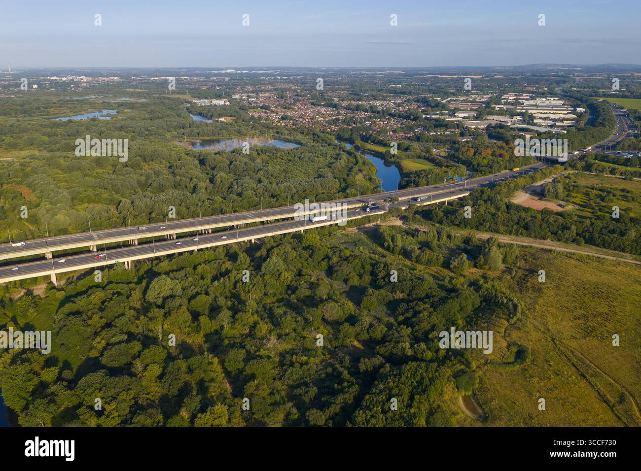 Immagine aerea dell'autostrada M6 sul viadotto di Thelwall che attraversa il fiume Mersey vicino a Warrington, con lussureggianti boschi verdi e campagna aperta Foto Stock