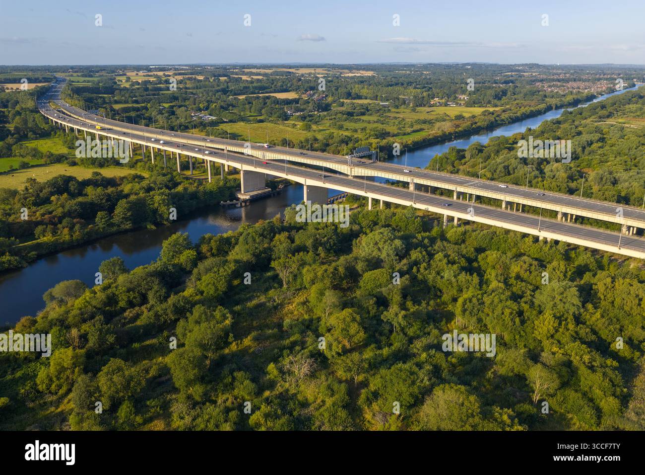 Immagine aerea dell'autostrada M6 sul viadotto di Thelwall che attraversa il fiume Mersey vicino a Warrington, con lussureggianti boschi verdi e campagna aperta Foto Stock
