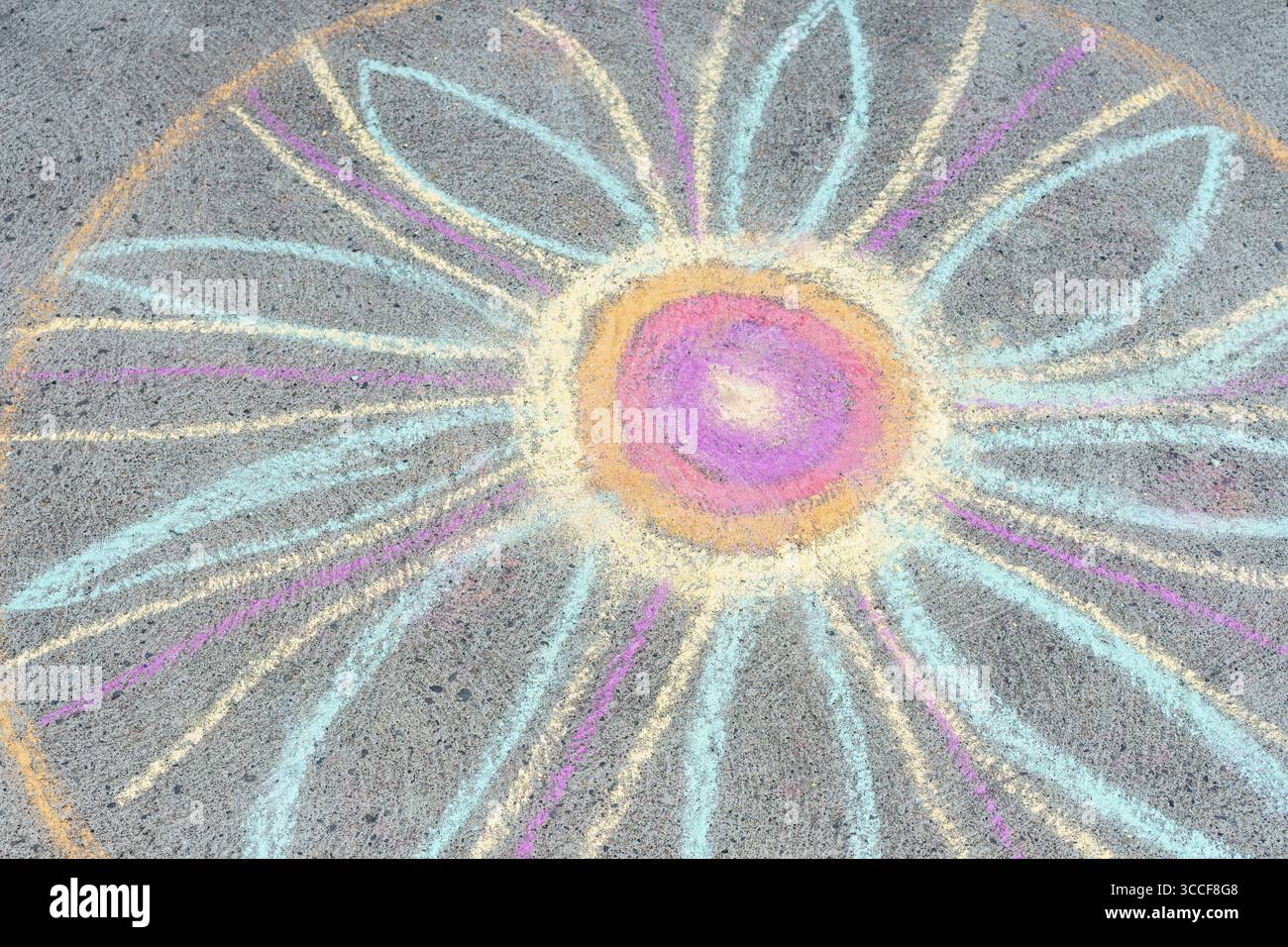 Il colorato fiore di gesso con petali pastello e un centro viola-arancione è disegnato su un marciapiede in simmetria circolare. Foto Stock