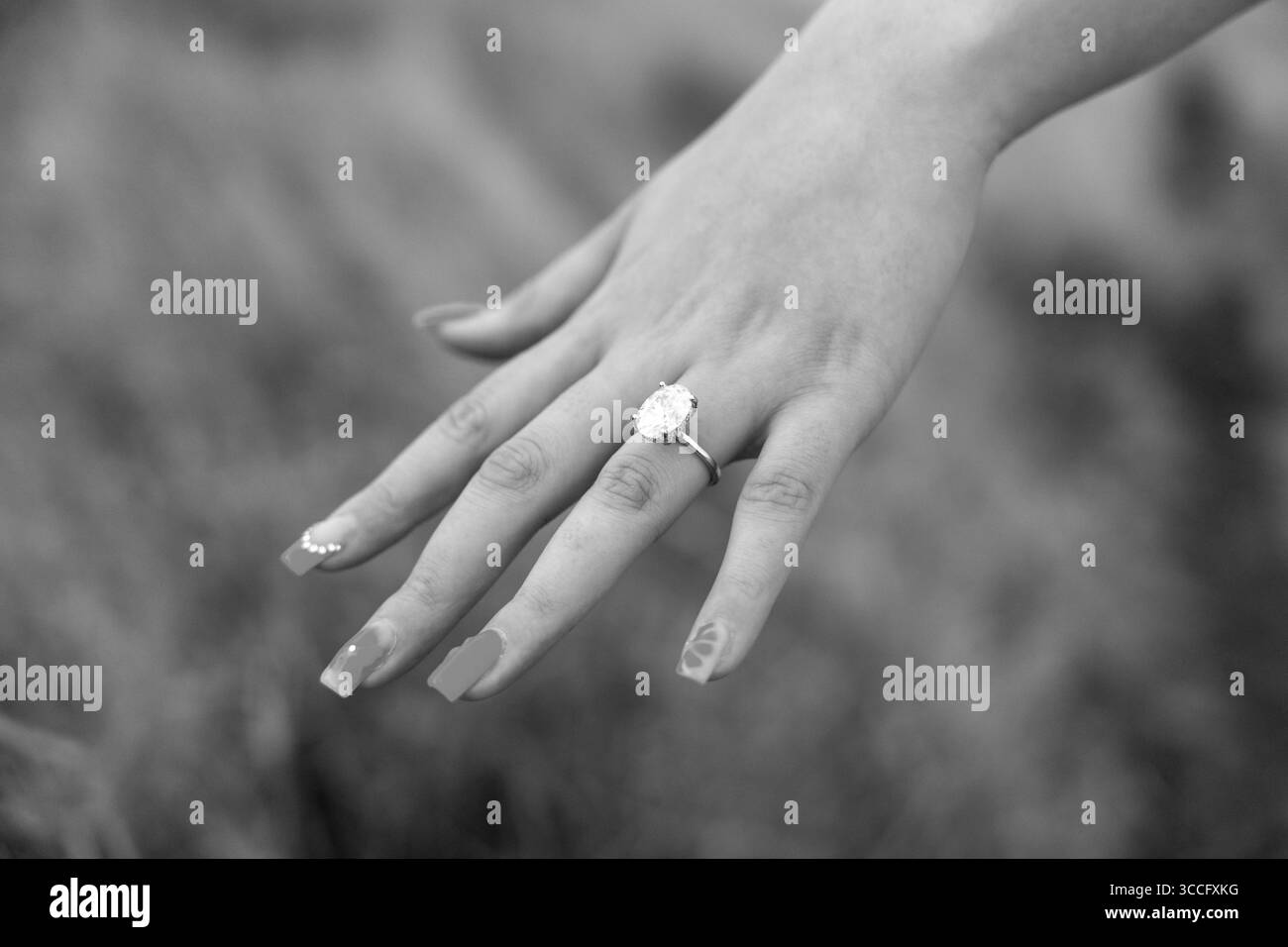 Primo piano della mano di una donna che mostra un anello di fidanzamento diamantato, catturando un momento tranquillo di amore, eleganza e promessa di un impegno senza tempo Foto Stock