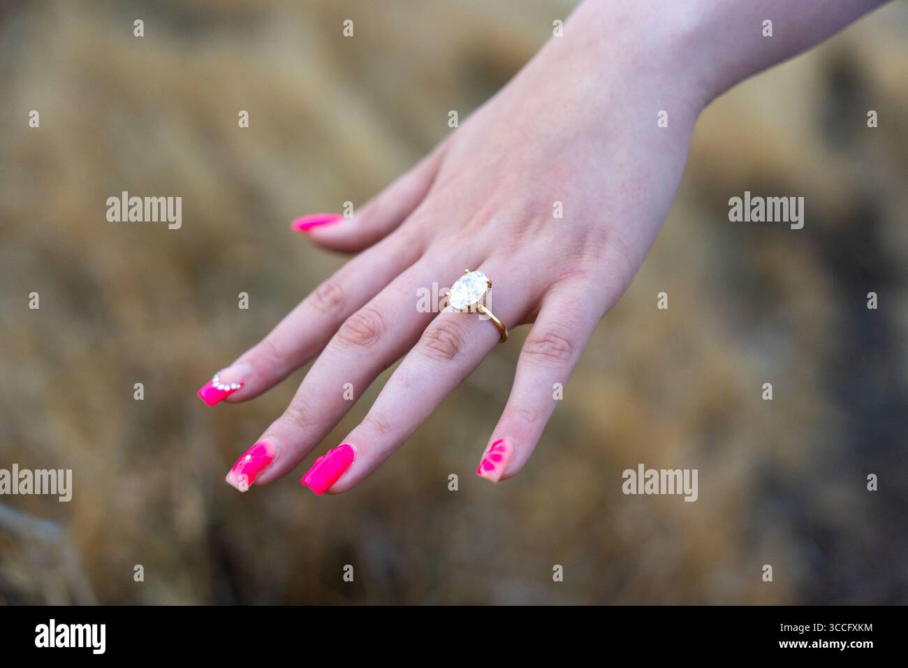 Primo piano della mano di una donna che mostra un anello di fidanzamento diamantato, catturando un momento tranquillo di amore, eleganza e promessa di un impegno senza tempo Foto Stock