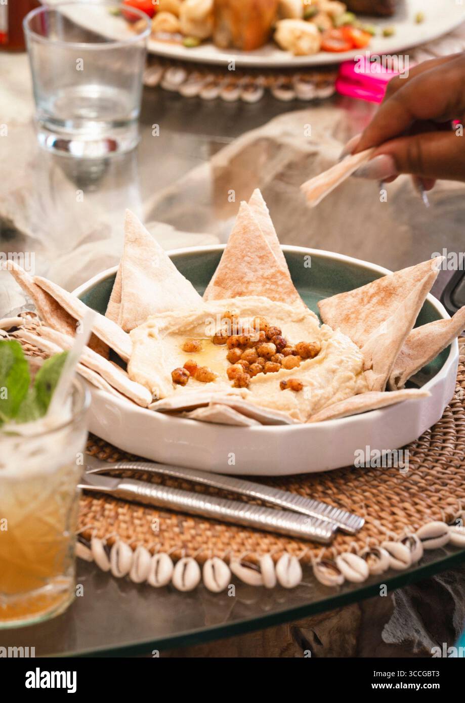 Hummus e piatto di pane in un ristorante sulla spiaggia con tavolo Foto Stock
