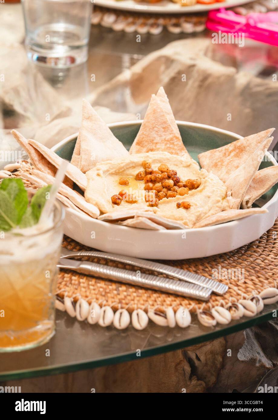 Hummus e piatto di pane in un ristorante sulla spiaggia con tavolo Foto Stock