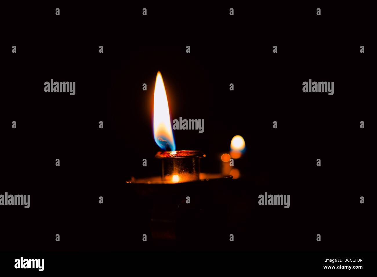 Candele accese e spente in un candelabro su sfondo scuro, evocando calore e memoria. Foto Stock