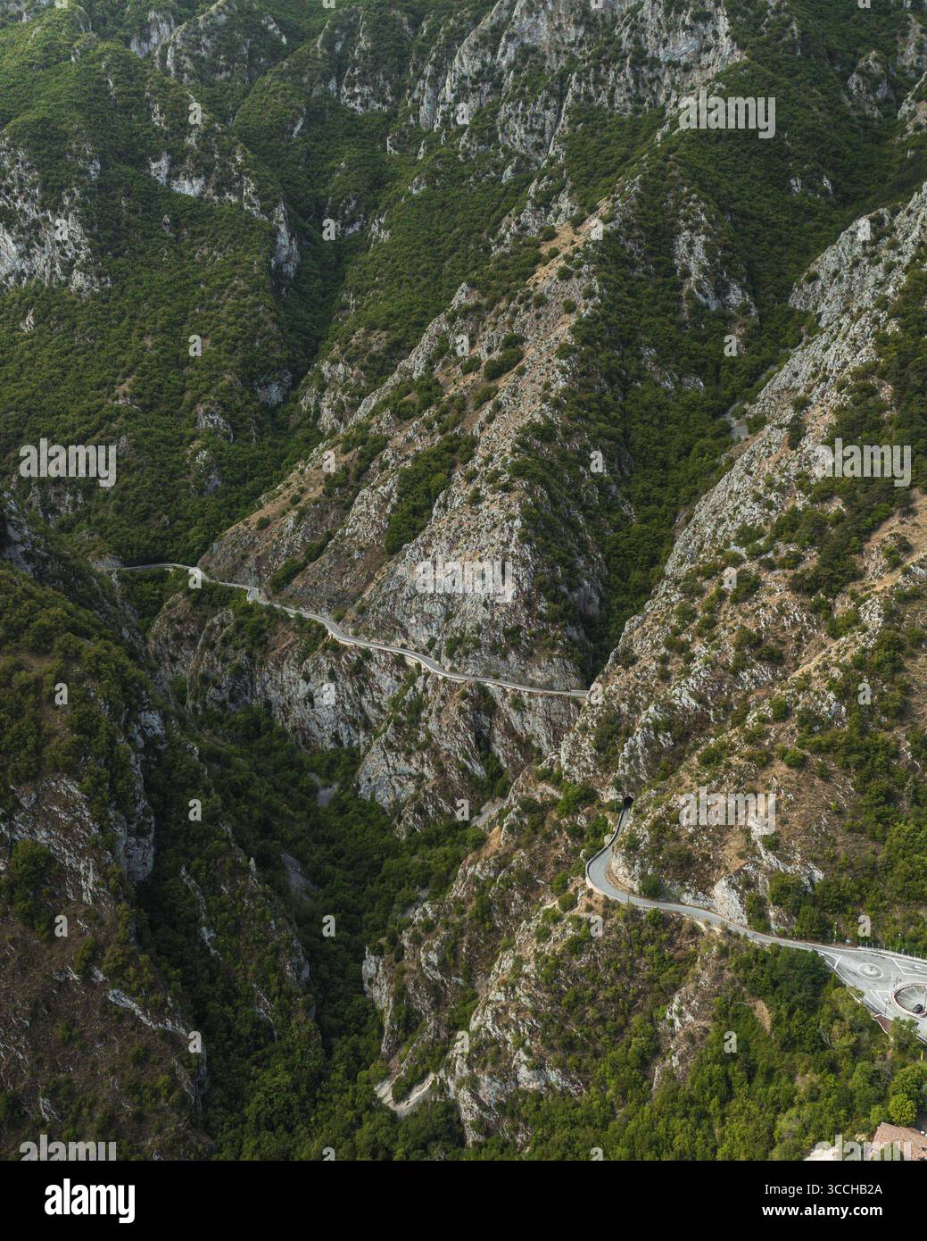 Vista aerea di una strada tortuosa che serpeggia tra le aspre e verdeggianti montagne, un arazzo di luci e ombre che dipinge le ripide pendici, Gole del Sagittario, Abruzzo, Italia. Foto Stock