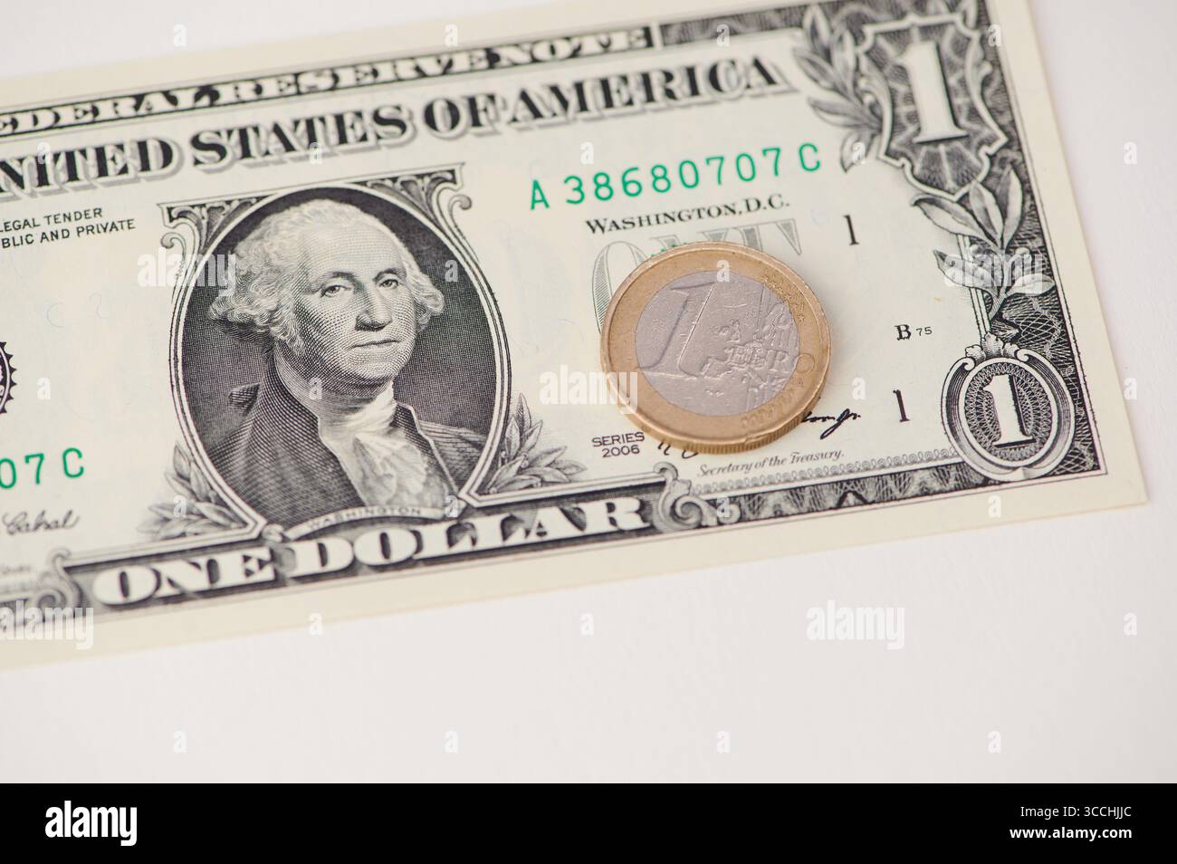 Una banconota da un dollaro si trova su una superficie accanto a una moneta in euro che mostra un contrasto monetario. Foto Stock