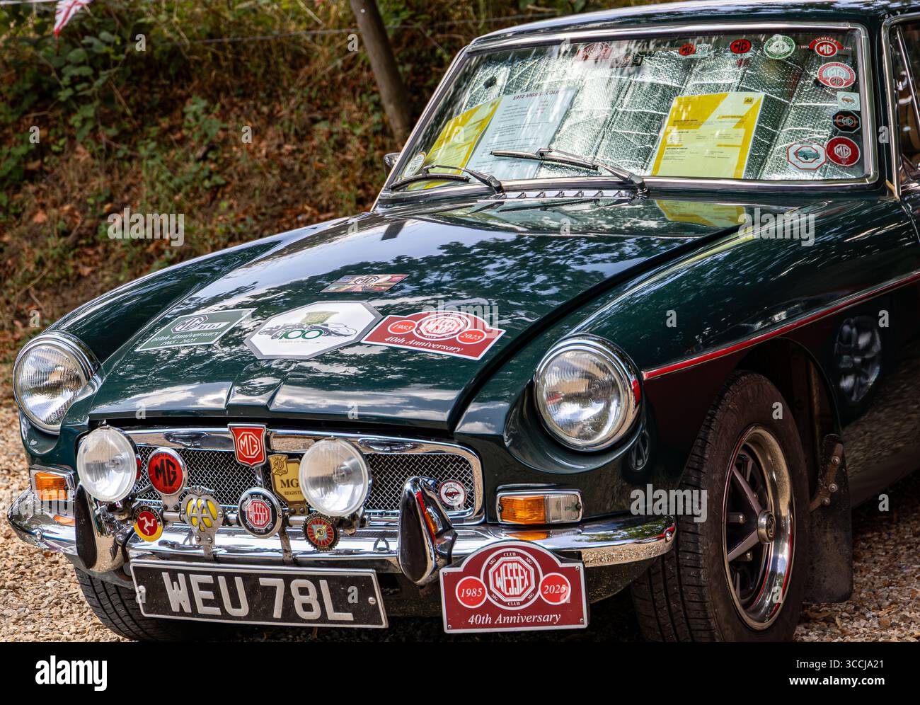 Classica auto sportiva MG verde ornata da vari badge commemorativi e documenti esposti sul classico parabrezza/parabrezza Foto Stock