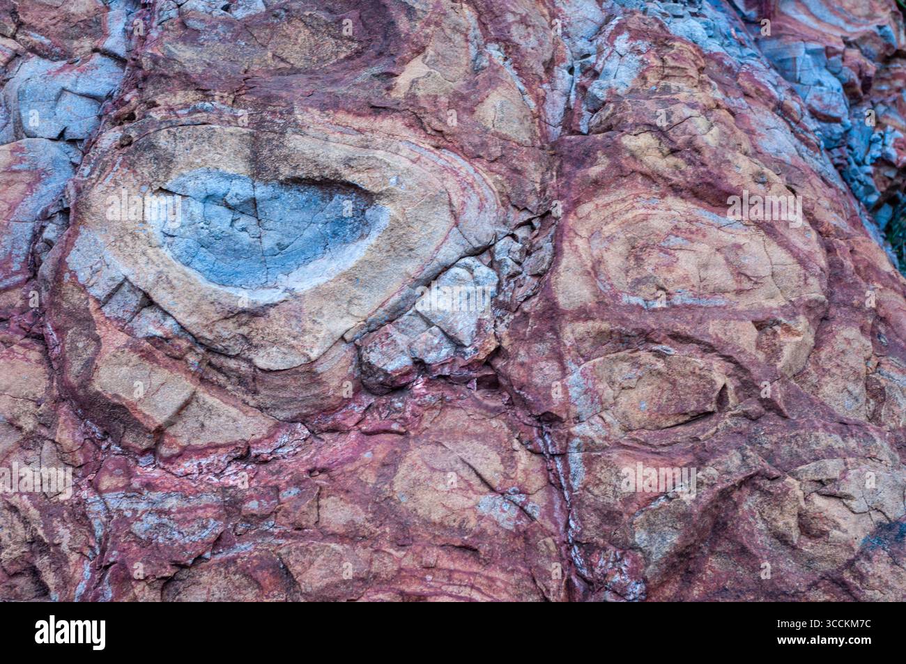 Una roccia con un motivo a turbolenza blu e marrone. La roccia è ruvida e frastagliata. I colori blu e marrone creano un senso di profondità e consistenza Foto Stock