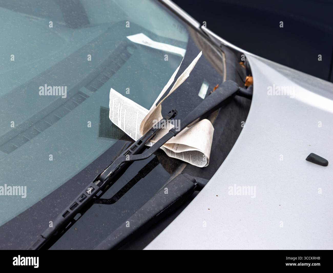 Una vista ravvicinata di un biglietto di violazione del parcheggio nascosto sotto la spazzola del tergicristallo di un parabrezza polveroso di un'auto a Soller, Maiorca. Foto Stock