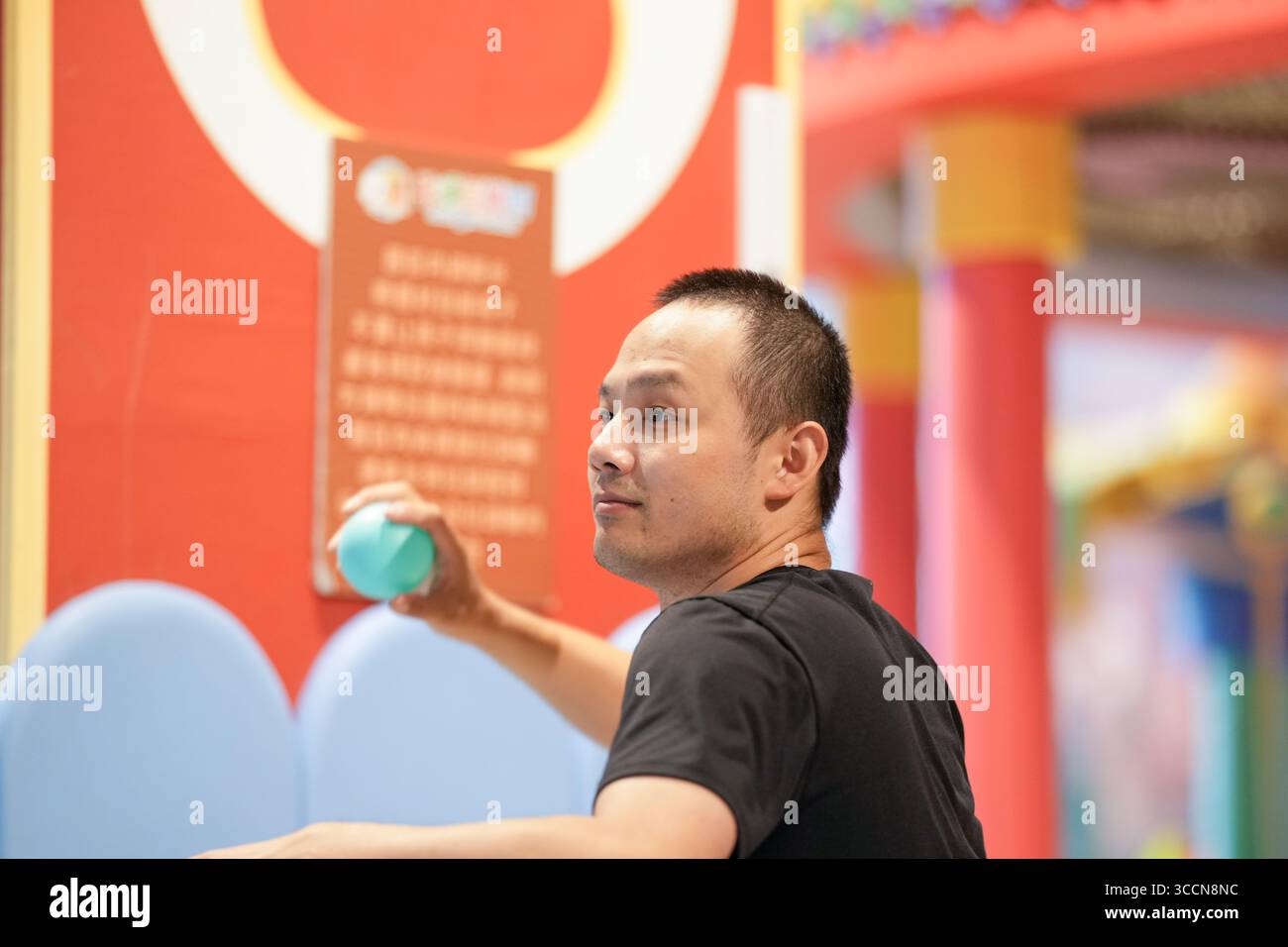 Adulti cinesi di 30 anni giocano in una piscina di palline di plastica in un'area giochi al coperto. Distretto di Hongkou, Shanghai, Cina. Primavera. Foto Stock