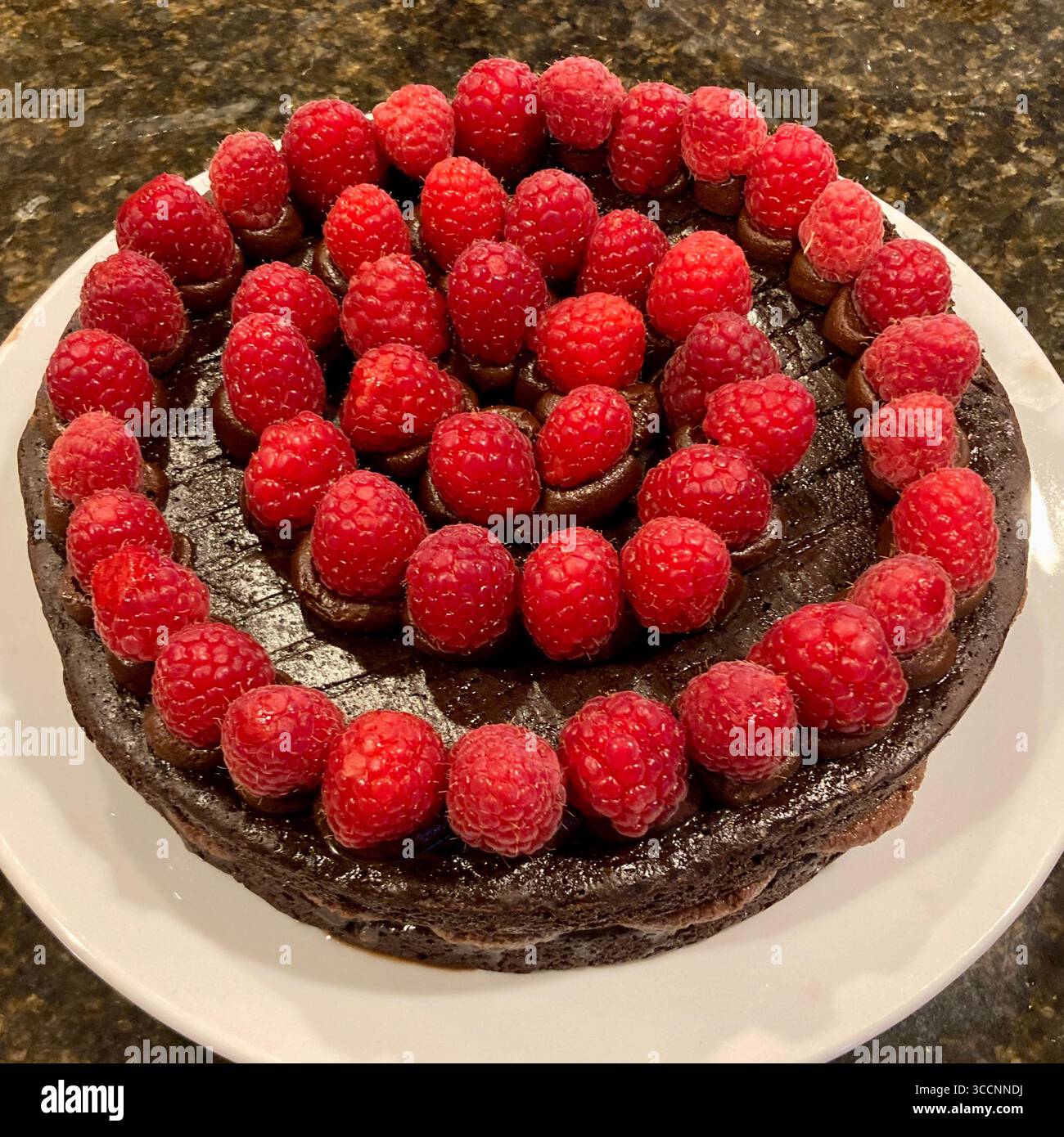 Una torta al cioccolato è ricoperta da lamponi freschi. - Immagine stock catturata con smartphone