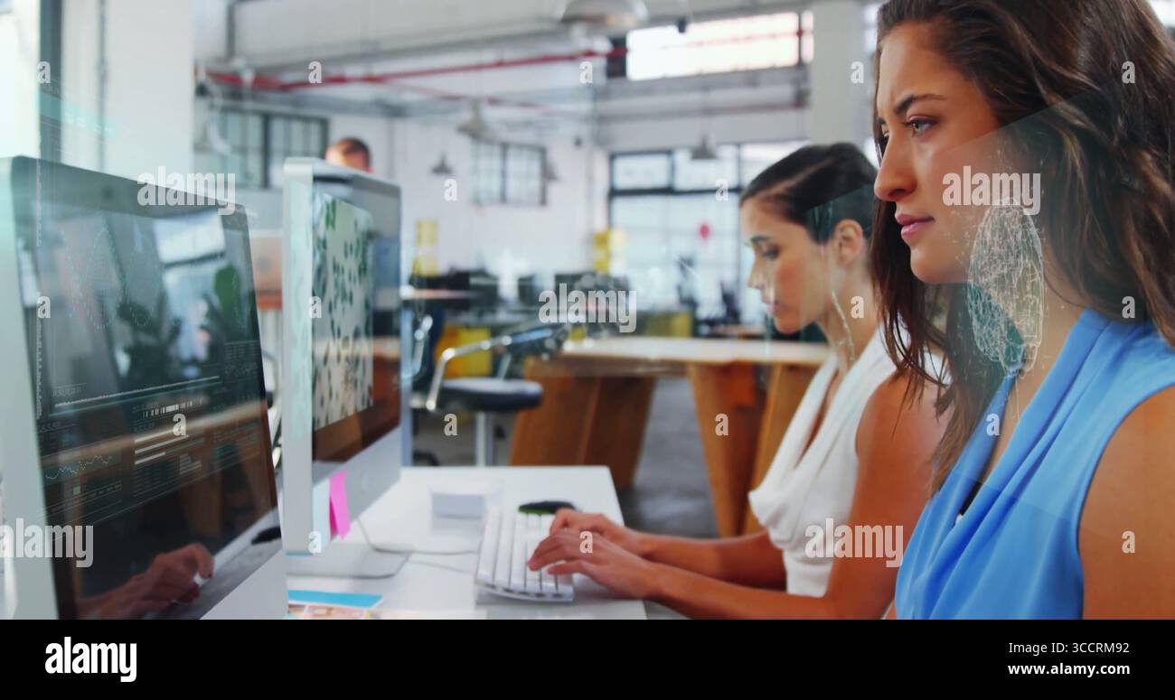 Due donne che lavorano in camicia senza maniche che scrivono sui monitor alla scrivania in un ufficio open space, spazio fotocopie Foto Stock