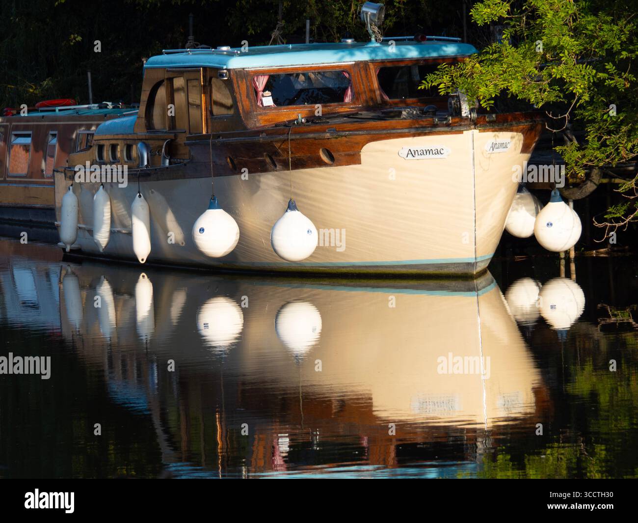 Casa galleggiante ormeggiata sul Tamigi ad Abingdon, con boe sospese. È interessante notare che questi dispositivi anticollisione/ancoraggio riempiti di schiuma sembrano avere molti nomi, variamente - parafanghi, boe per imbarcazioni, paraurti, parafanghi con boa... scegliete voi. Ma qui le boe e i loro riflessi nel fiume rendono un'interessante composizione astratta... Foto Stock