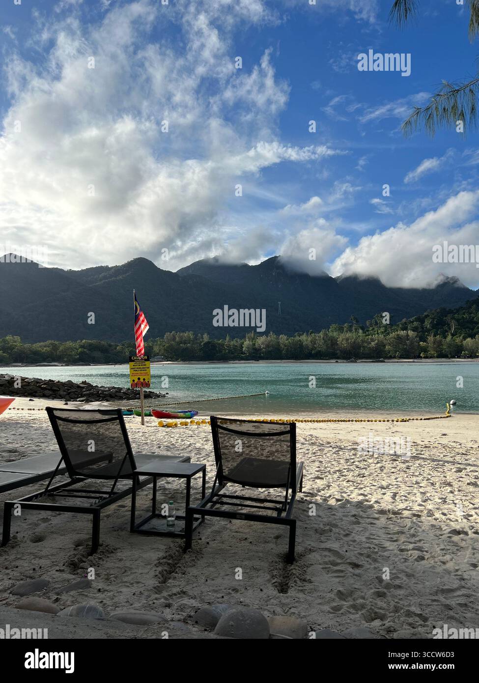 Sedie a sdraio che si affacciano sulle acque turchesi e sullo sfondo di una montagna a Langkawi, Malesia. Foto Stock