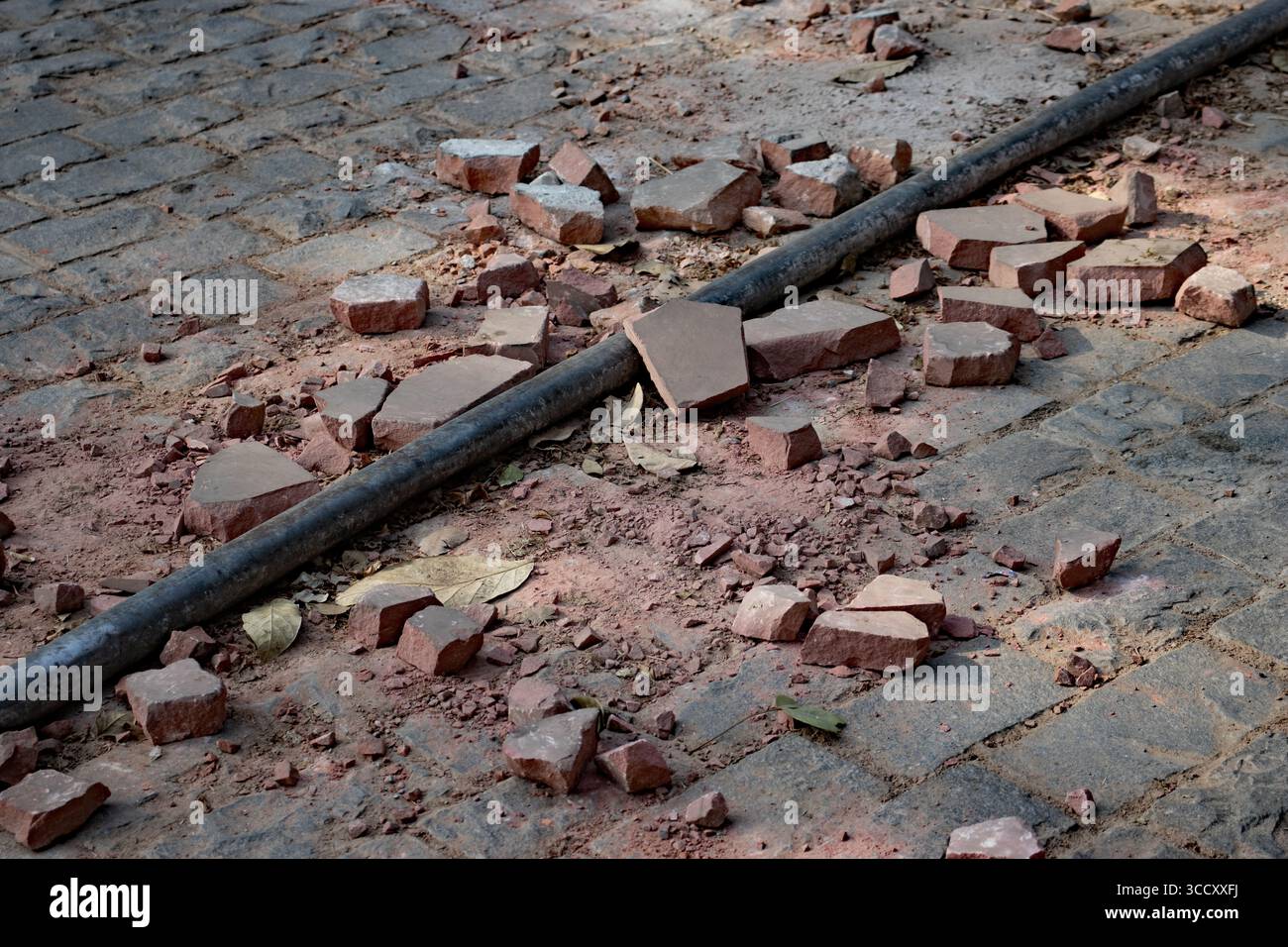 Pavimentazione in mattoni rossi rotti con tubo dell'acqua nel nord-ovest dell'India Foto Stock