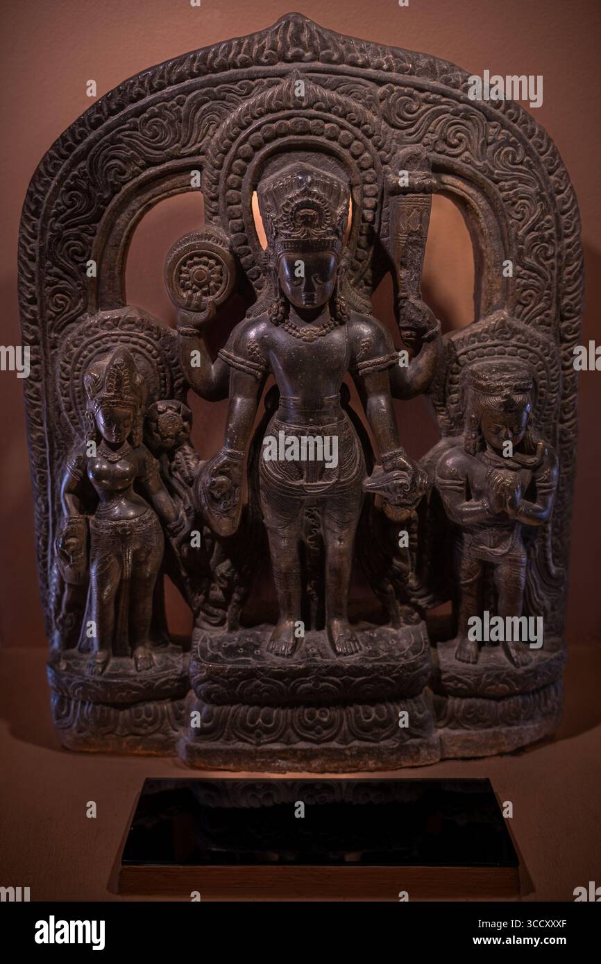 Antica statua in pietra scolpita con figure sacre della famiglia divina indù, che riflette secoli di arte himalayana. Foto Stock