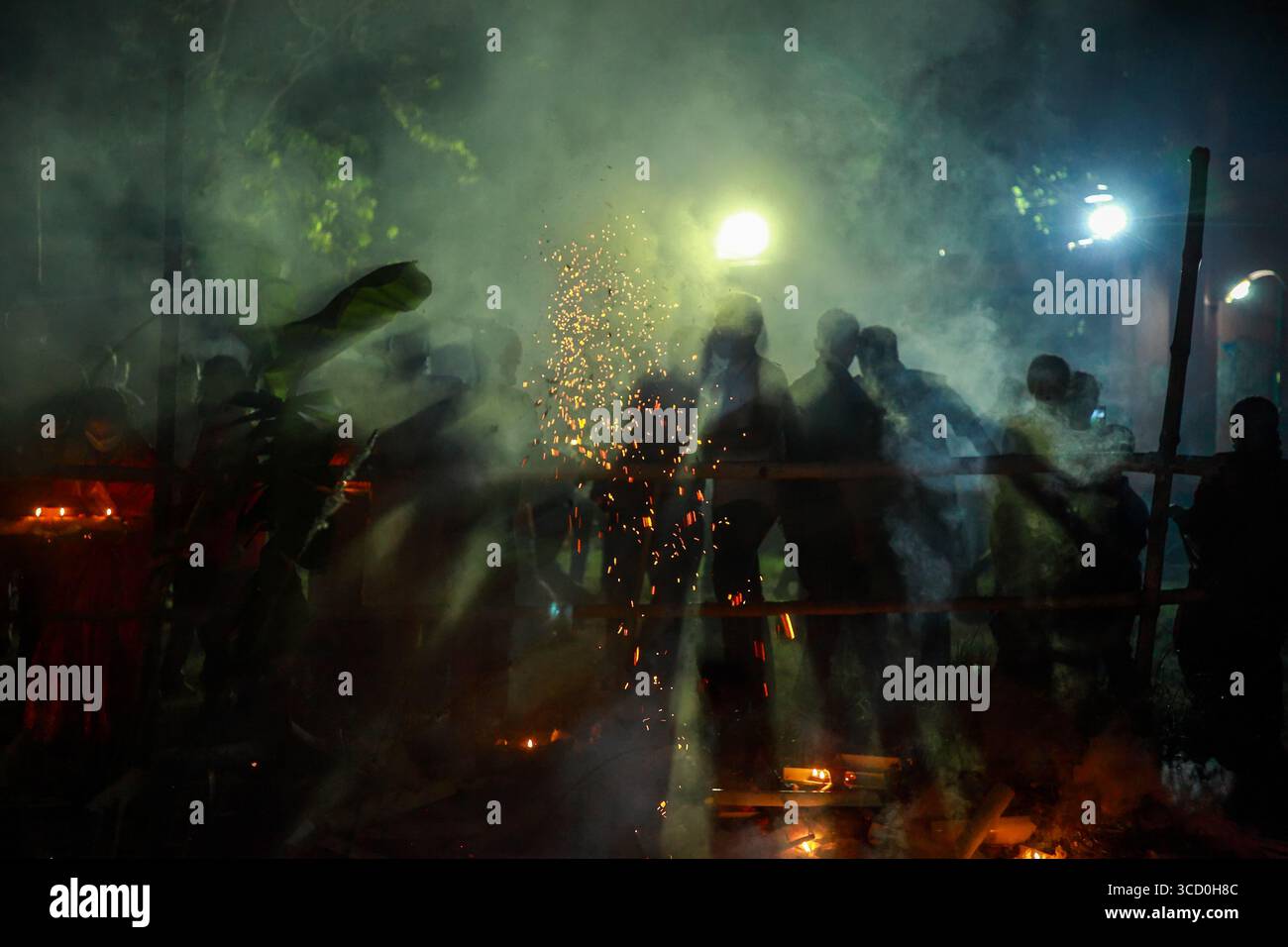 Narayanganj, Bangladesh - 7 novembre 2020: Veduta di una folla avvolta dal fumo e dalla luce, che getta lunghe ombre mentre si radunano vicino a una struttura. Foto Stock