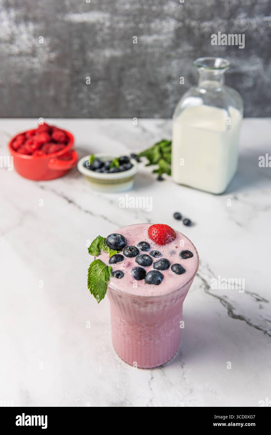 Bibita al mirtillo naturale: Bevanda frizzante con succo di mirtillo appena spremuto, limone e menta, servita in un bicchiere con ghiaccio geometrico Foto Stock