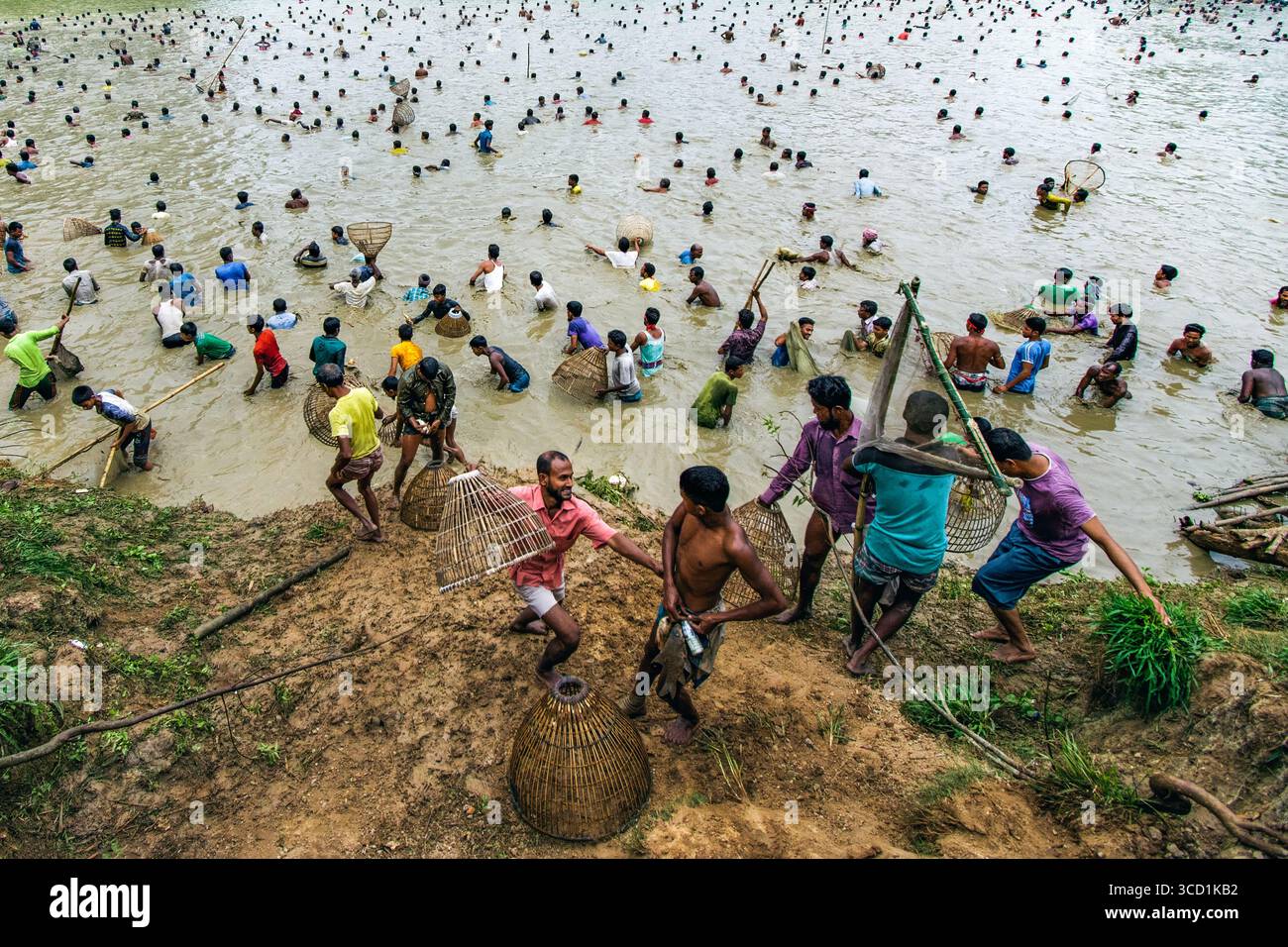 Bogura, Bangladesh - 24 marzo 2018: Vista di una vivace comunità che pesca in acque torbide, i loro vestiti colorati un netto contrasto con le rive fangose del fiume. Foto Stock