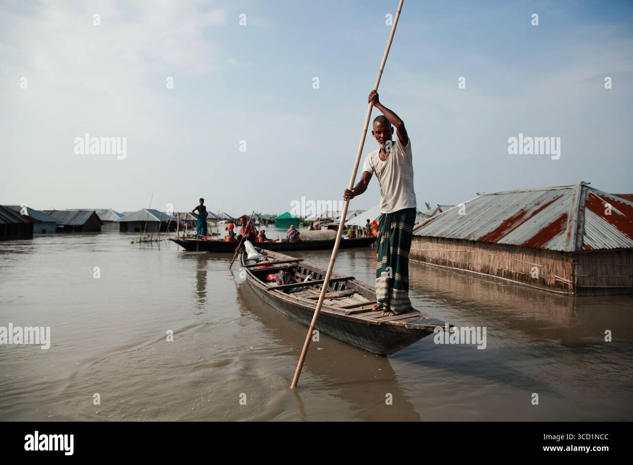 Kurigram, Bangladesh - 21 giugno 2022: Veduta di un uomo che naviga nelle acque alluvionali in barca, case sommerse, riflettendo la dura realtà della vita in mezzo alle acque che si innalzano. Foto Stock