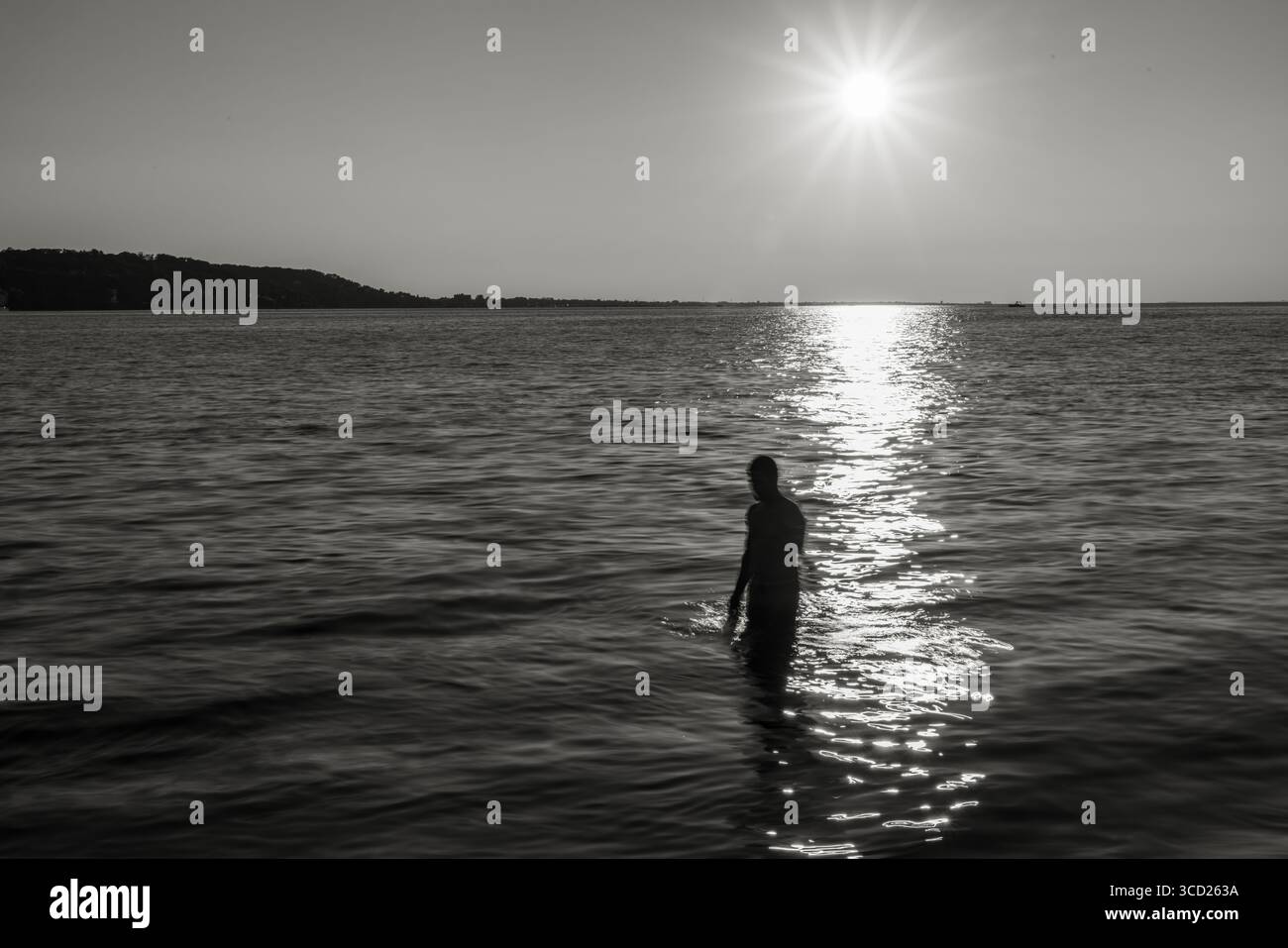 Silhouette di persona in piedi nell'oceano al tramonto in bianco e nero Foto Stock