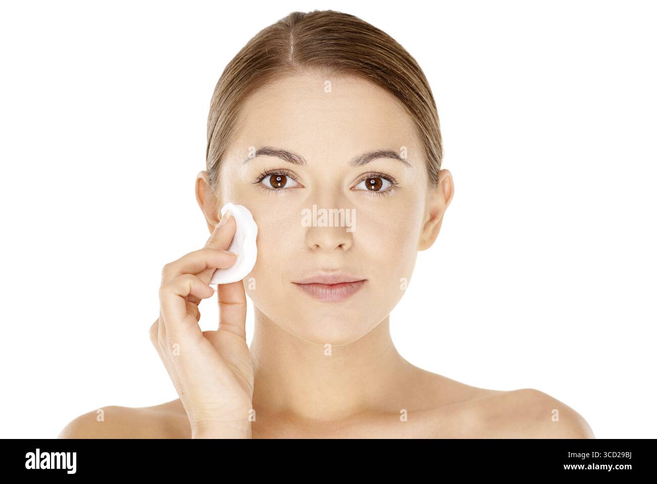 Fresco ritratto naturale di una bella giovane donna che si pulisce il viso con un tampone di cotone che le pulisce la guancia isolata su bianco Foto Stock