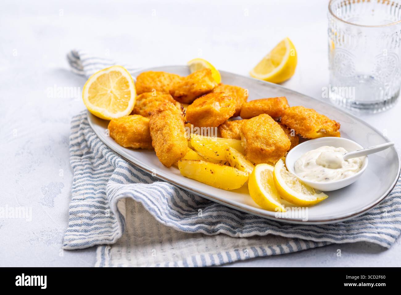 Pesce e patatine tradizionali con salsa al limone e tartaro sul piatto da portata Foto Stock