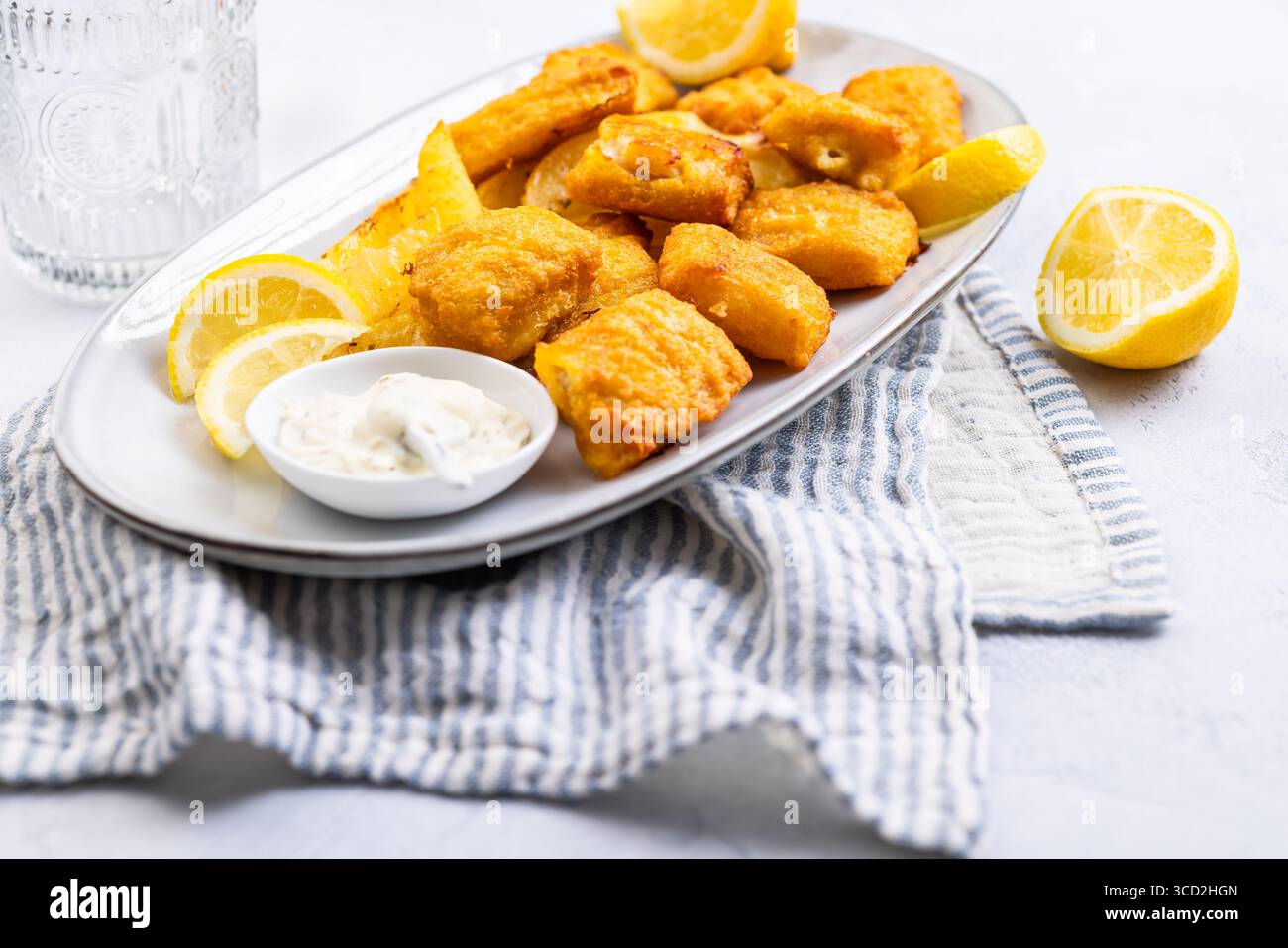 Pesce e patatine tradizionali con salsa al limone e tartaro sul piatto da portata Foto Stock