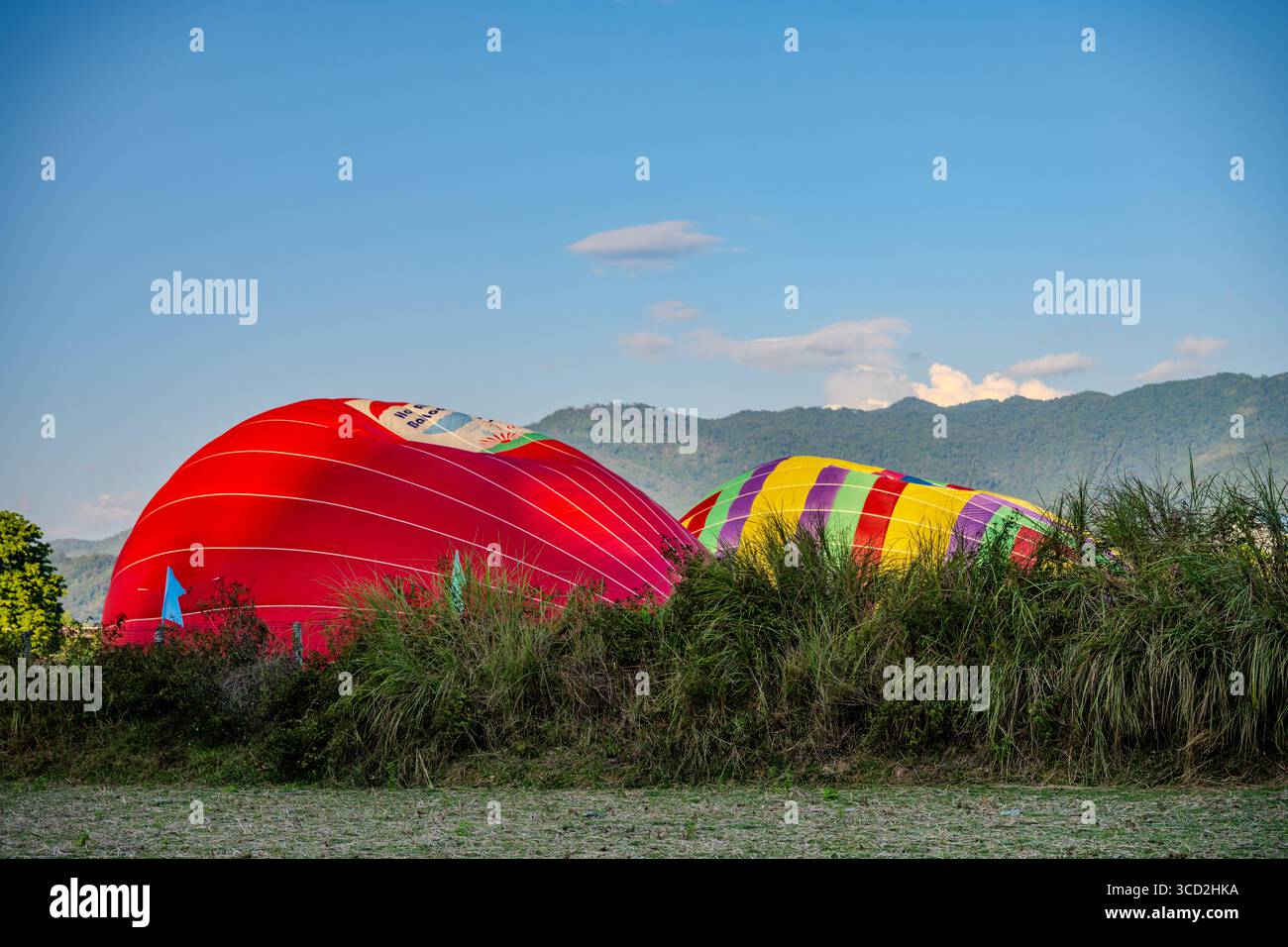 Palloni ad aria calda sgonfiati che riposano su Grass Field con sfondo di montagna durante il tramonto a Vang Vieng, Laos Foto Stock