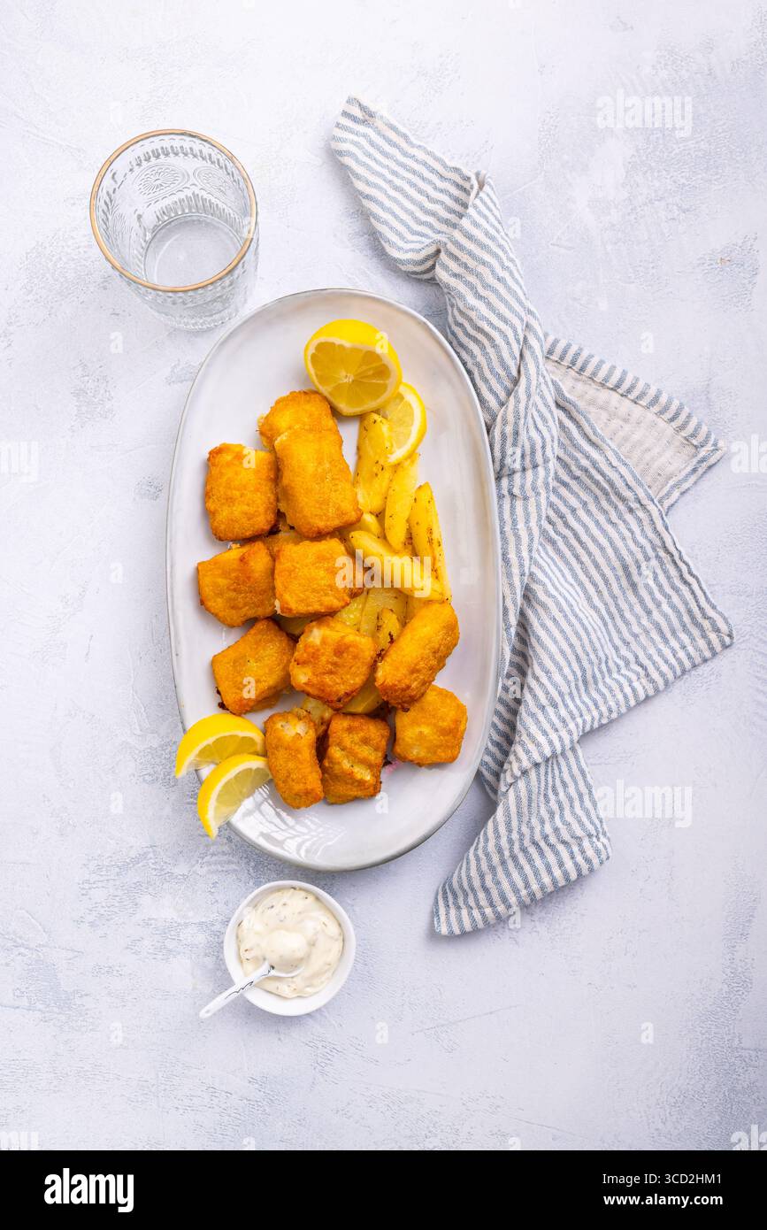 Pesce e patatine tradizionali con salsa al limone e tartaro sul piatto da portata Foto Stock