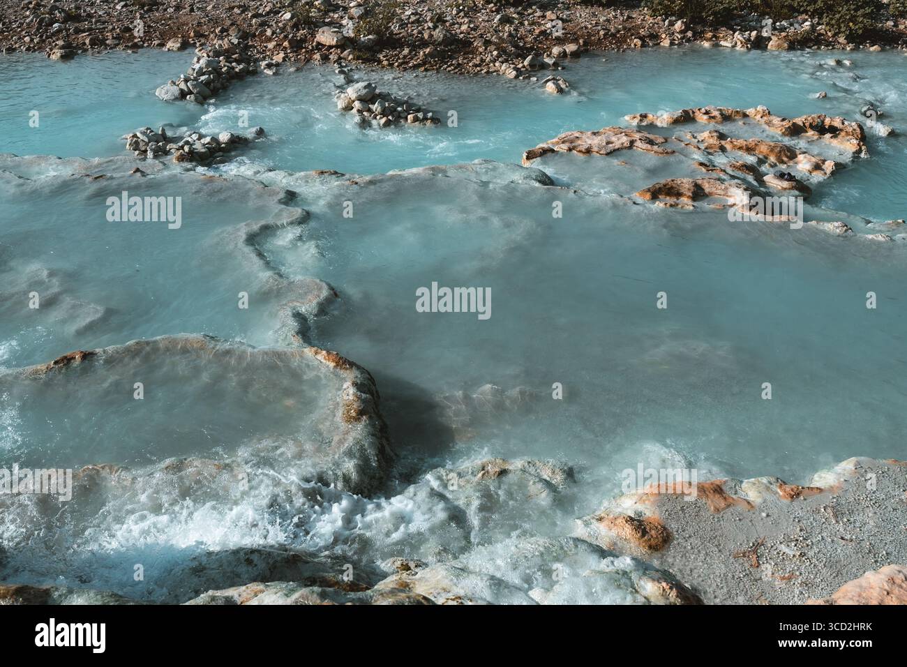 Vista delle acque termali azzurre che si infrangono su formazioni rocciose di travertino, creando un paesaggio etereo e surreale, Saturnia, Toscana, Italia. Foto Stock
