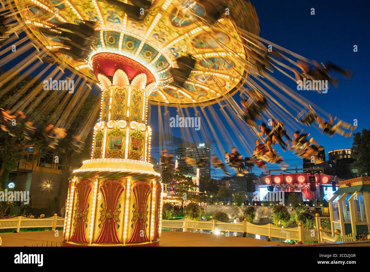 Giostra illuminata al parco divertimenti Tivoli di Copenaghen di notte Foto Stock