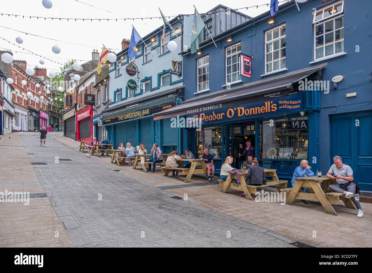 Persone sedute su tavoli da picnic fuori dal pub Peadar o'Donnell, Waterloo Street, Derry, County Londonderry, Irlanda del Nord, Regno Unito Foto Stock
