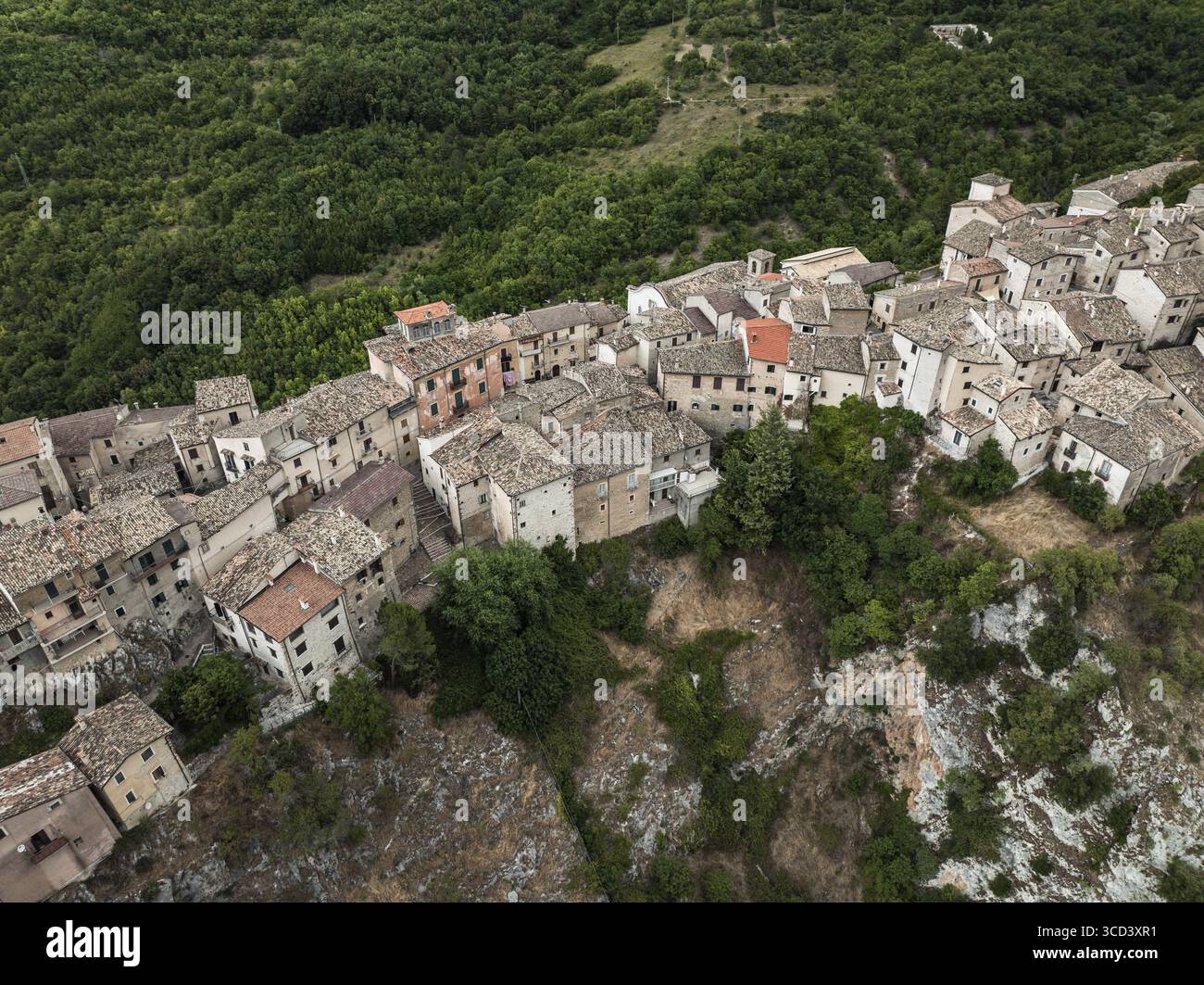 Vista aerea di antiche abitazioni aggrappate alla ripida collina, un arazzo di pietra e tetti di terracotta intemprati tra il verdeggiante abbraccio del Foto Stock