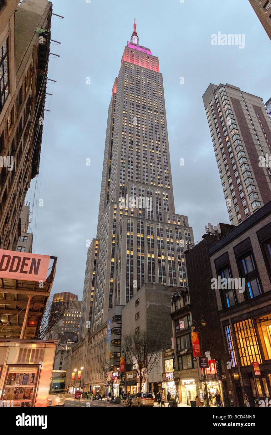 Vista a livello della strada guardando verso l'Empire State Building, Manhattan, New York, Stati Uniti, catturando l'architettura iconica e lo skyline della città, in prima serata Foto Stock