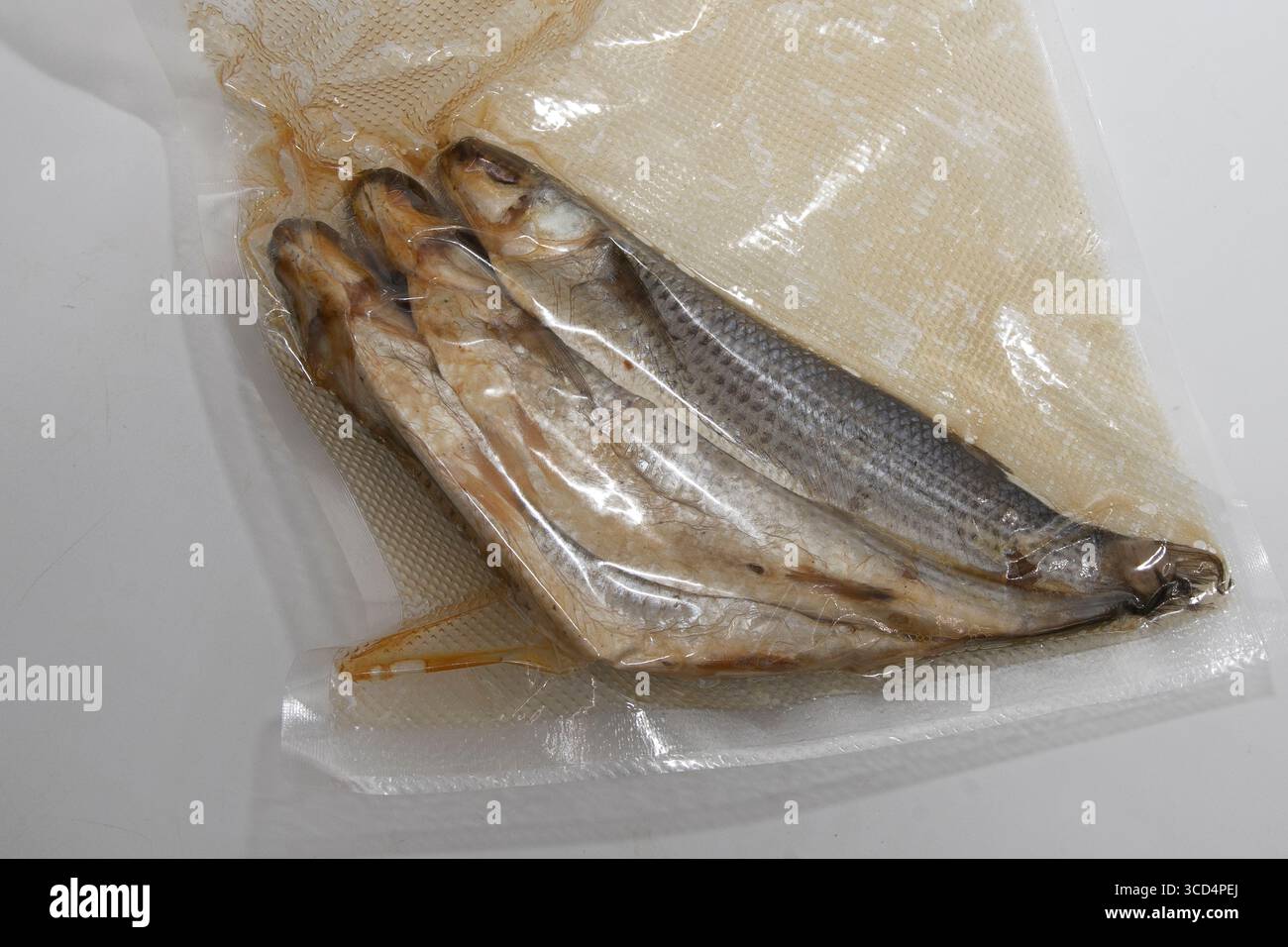 Primo piano di pesci secchi sigillati in un imballaggio sottovuoto trasparente. Prodotti a base di pesce conservati per lo stoccaggio, la vendita e la cucina tradizionale. Foto Stock