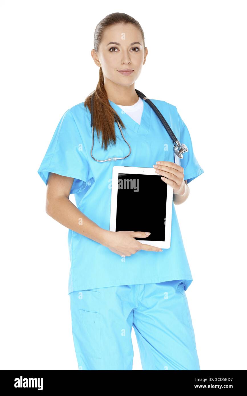Attraente e seria giovane medico o infermiera in scrub verdi con un tablet-pc o un notebook visualizzato sullo schermo delle mani visibile allo spettatore Foto Stock