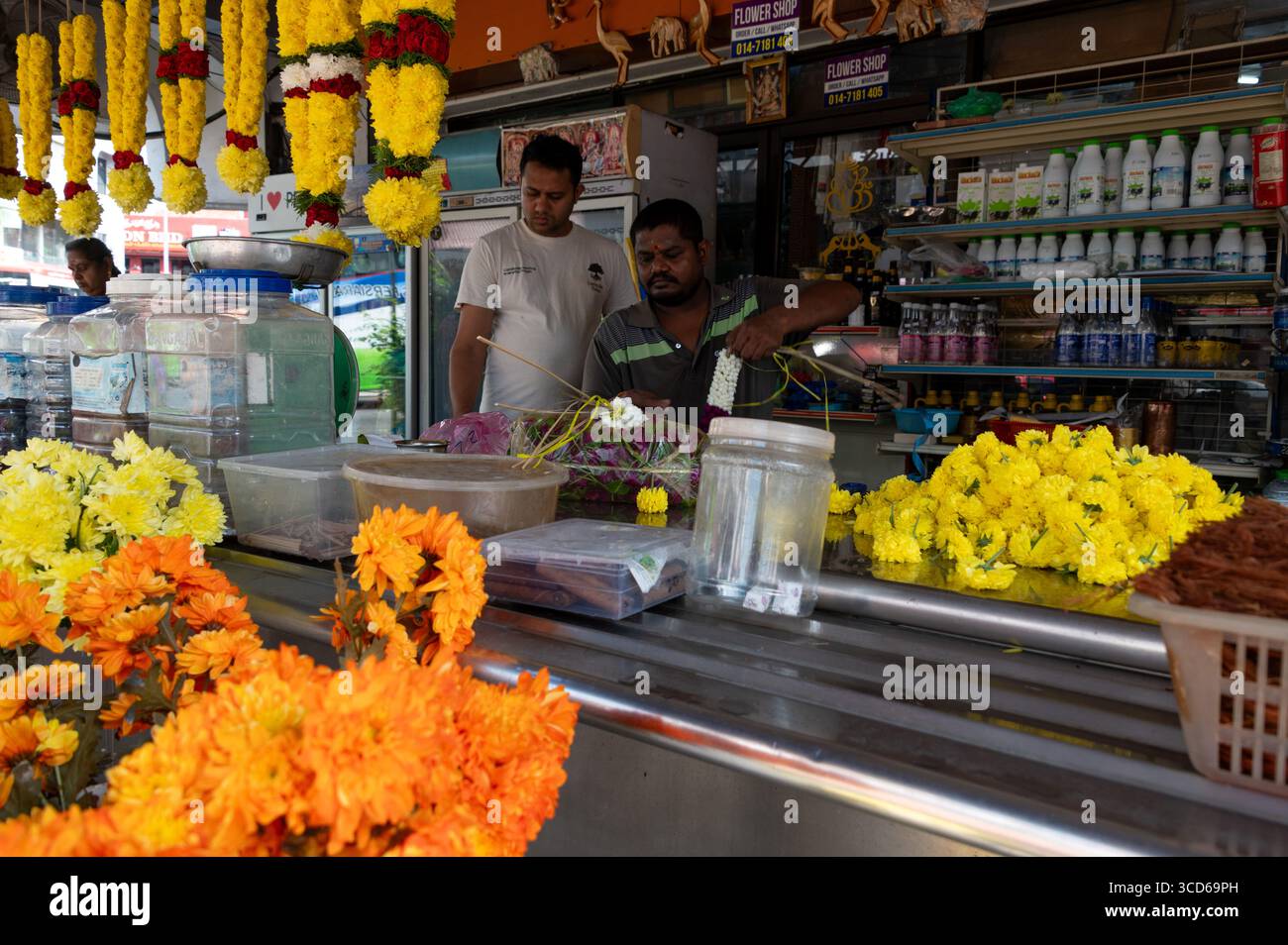 Una fila di colorate ghirlande di fiori di Marigold in vendita e altri prodotti indiani in Chulia Street nel quartiere di Little India a Georgetown, capitale Foto Stock
