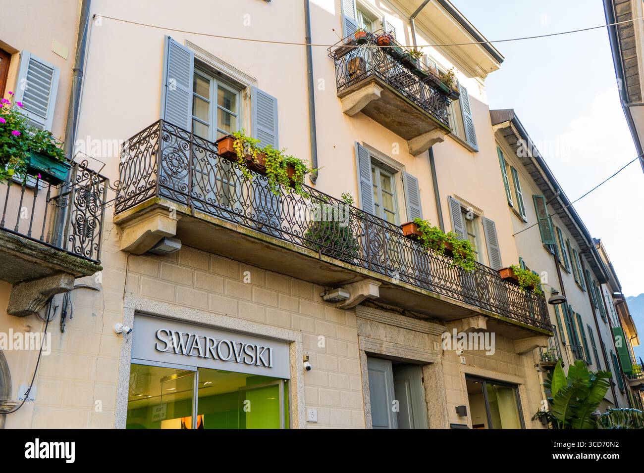 Facciata di una vecchia casa con balcone. Marchio Swarovski Store di Como con logo. Ingresso ufficiale al negozio. Italia, Como - 17 luglio 2025 Foto Stock