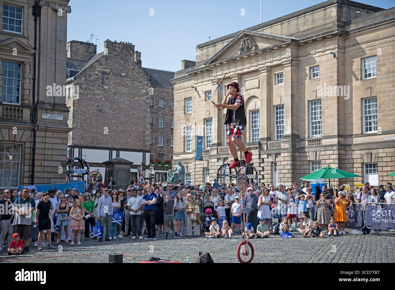 Edinburgh Festival Fringe, Royal Mile, 12 agosto 2025. 27 gradi centigradi per i visitatori e gli artisti di strada sulla High Street. Nella foto: Hunter si destreggia con oggetti appuntiti mentre mangia una mela in West Parliament Square. Credito: Arch White/alamy notizie dal vivo. Foto Stock